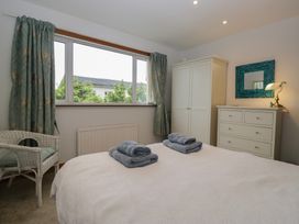 A bedroom with a bed, wardrobe, dresser, and window at Redwood in Ambleside
