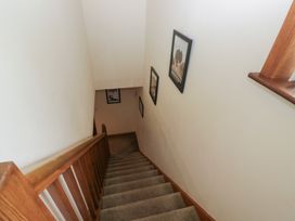 A staircase with a wooden handrail and pictures on the wall at Redwood in Ambleside