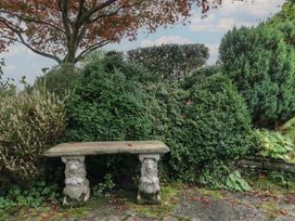 A garden with a stone bench surrounded by bushes at Redwood in Ambleside