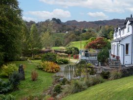 A garden view with a house and seating area at Goody Raise in Grasmere