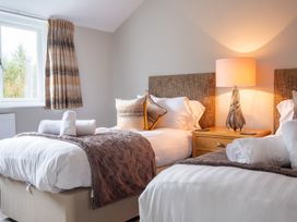 A bedroom with two beds and a bedside table at Goody Raise in Grasmere