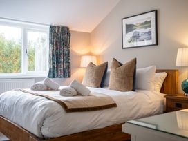 A bedroom with a bed, bedside table and curtains at Goody Raise in Grasmere