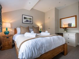 A bedroom with a bed, nightstand, lamp, mirror, and desk at Goody Raise in Grasmere