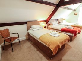 A bedroom with three beds and a chair at Hawkshead Hall in Hawkshead