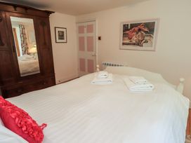 A bedroom with a bed, towels, wardrobe and artwork at Rose Cottage Coniston