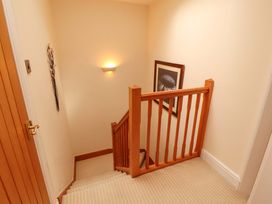 A staircase with a handrail and wall light at Durham Bridge Barn in Crosthwaite