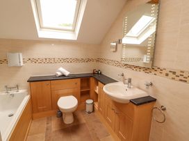 A bathroom with a bathtub, toilet, sink and mirror at Durham Bridge Barn in Crosthwaite
