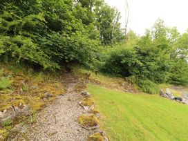 A garden path leading through bushes and trees at Durham Bridge Barn Crosthwaite