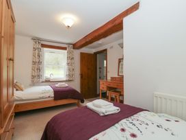 A bedroom with two beds and a dresser at Cygnet Cottage Thornthwaite