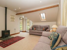 A living room with a sofa and wood stove at Cygnet Cottage in Thornthwaite