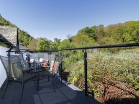 A balcony with chairs and a table overlooking greenery at Cygnet Cottage Thornthwaite
