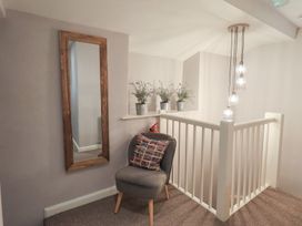 A hallway with a mirror and chair at Chapel Hill Cottage in Ambleside