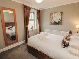 A bedroom with a bed and mirror at Gildabrook Cottage in Bowness