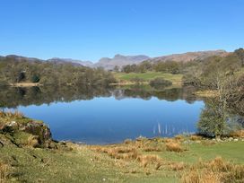 A lake with grassy banks trees and mountains in the background at Puddleduck in Skelwith Bridge near Chapel Stile