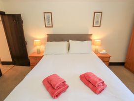 A bedroom with a double bed with white bedding and pink towels on top two bedside tables with lamps and framed artwork on the wall at The Cottage in Keswick