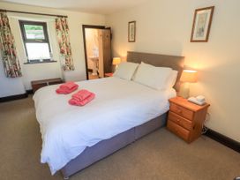A bedroom with a double bed white bedding pink towels wooden bedside tables lamp window with floral curtains at The Cottage in Keswick