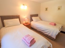 A bedroom with two single beds with white bedding and pink towels on the beds at The Cottage in Keswick