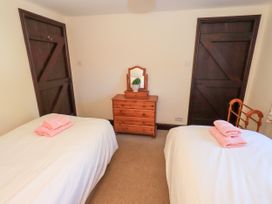 A bedroom with two single beds with pink towels a wooden chest of drawers and two dark wooden doors at The Cottage in Keswick