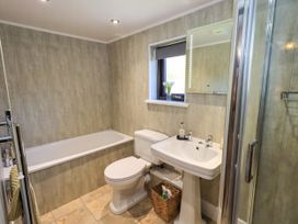 A bathroom with a bathtub toilet sink shower and a window with flowers at The Cottage in Keswick