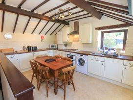 A kitchen with wooden ceiling beams wooden table and chairs white cabinets and appliances at The Cottage in Keswick