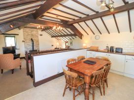 A dining area with wooden table and chairs next to a kitchen and a living room with armchairs and a fireplace at The Cottage in Keswick