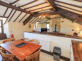 A dining area with a wooden table and chairs next to a living room with a wood stove and TV at The Cottage in Keswick