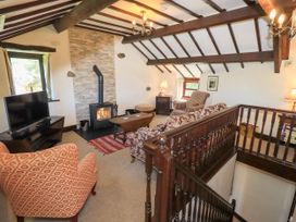 A sitting room with wooden ceiling beams a fireplace and patterned armchairs at The Cottage in Keswick