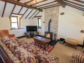 A living room with patterned sofas a wood stove and a television at The Cottage in Keswick