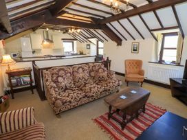 A living room with patterned sofas a wooden coffee table and a kitchen counter at The Cottage in Keswick