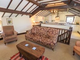 A living room with a patterned sofa armchair and wooden coffee table next to an open kitchen area at The Cottage in Keswick