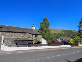 A stone cottage with a parking area and hills in the background at The Cottage in Keswick