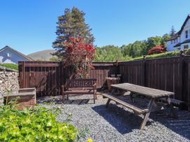 A small fenced patio area with a wooden bench table and bench seating at The Cottage in Keswick