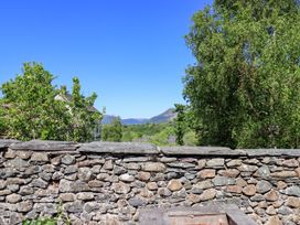 A stone wall with greenery and hills in the background at The Cottage in Keswick