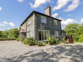 A house with stone exterior and large windows at Elterwater Lodge in Elterwater