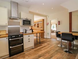 A kitchen with an oven, microwave and bar stools at Elterwater Lodge in Elterwater