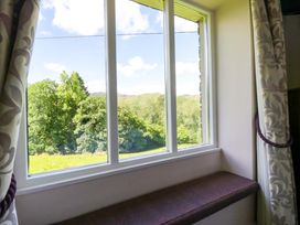 A window with curtains overlooking a green landscape at Elterwater Lodge in Elterwater