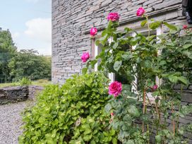 An outdoor view of a stone wall with roses and a window at Elterwater Lodge in Elterwater