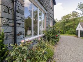 A stone exterior of a house with a window and garden at Elterwater Lodge in Elterwater
