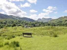 A landscape with a bench overlooking fields and mountains at Elterwater Lodge in Elterwater