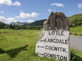 A directional sign in a grassy area with mountains in the background at Elterwater Lodge Elterwater