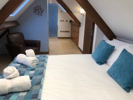A bedroom with a bed and chair at Dancing Beck Cottage in Millbeck