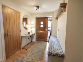 A hallway with a mirror, lamp, table and coat rack at No 7, Ambleside