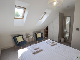 A bedroom with a bed, two chairs, and a mirror at No 7 in Ambleside