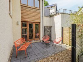 An outdoor patio with red chairs and a stone wall at No 7 Ambleside