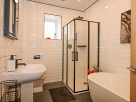 A bathroom with a pedestal sink toilet glass shower enclosure and bathtub at Sea View in Penrhyn Bay