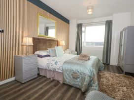 A bedroom with a double bed bedside tables lamps a wardrobe and a window with curtains at Sea View in Penrhyn Bay