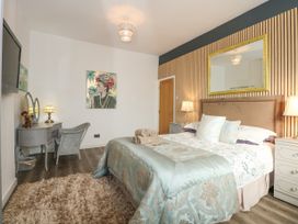 A bedroom with a double bed bedside tables a dressing table chair and a wall mirror at Sea View in Penrhyn Bay