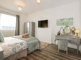 A bedroom with a bed a vanity table wardrobe and a wall-mounted television at Sea View in Penrhyn Bay