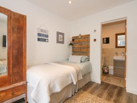 A bedroom with a single bed a wooden wardrobe and an open door leading to a bathroom at Sea View in Penrhyn Bay