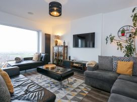 A living room with sofas a coffee table and a wall-mounted television at Sea View in Penrhyn Bay